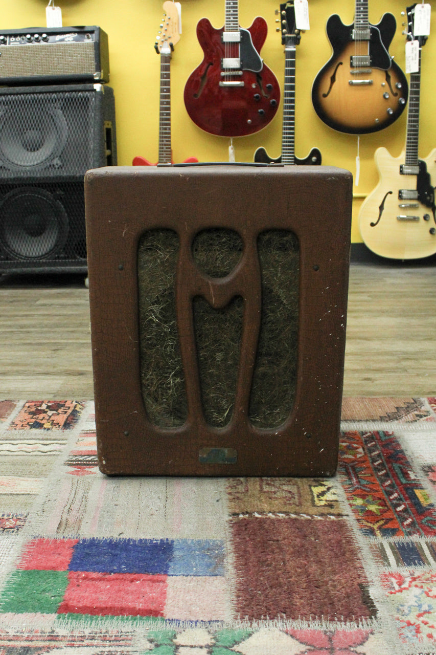 Front view of a brown, alligator-textured combo amp with three vertical speaker cutouts, revealing a light-colored grille cloth.