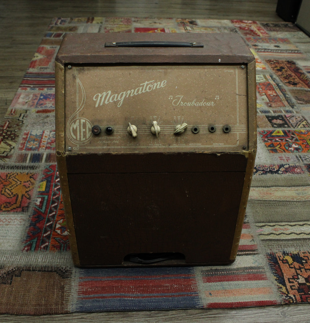 Front view of a brown vintage combo amp with a tan control panel, four cream knobs, and four input jacks.
