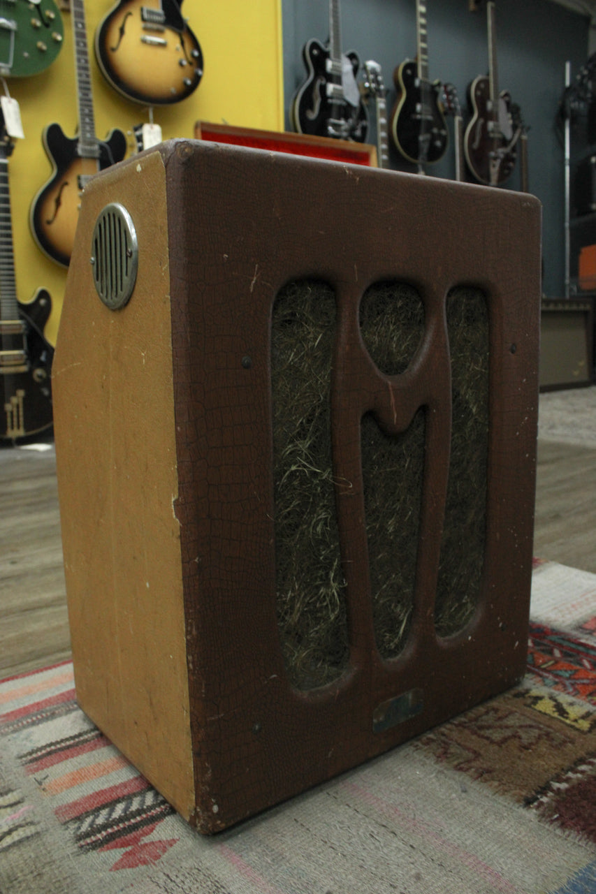 The brown, alligator-textured amp is angled to show its tan side panel with a round metal vent and the front grille with three vertical cutouts.