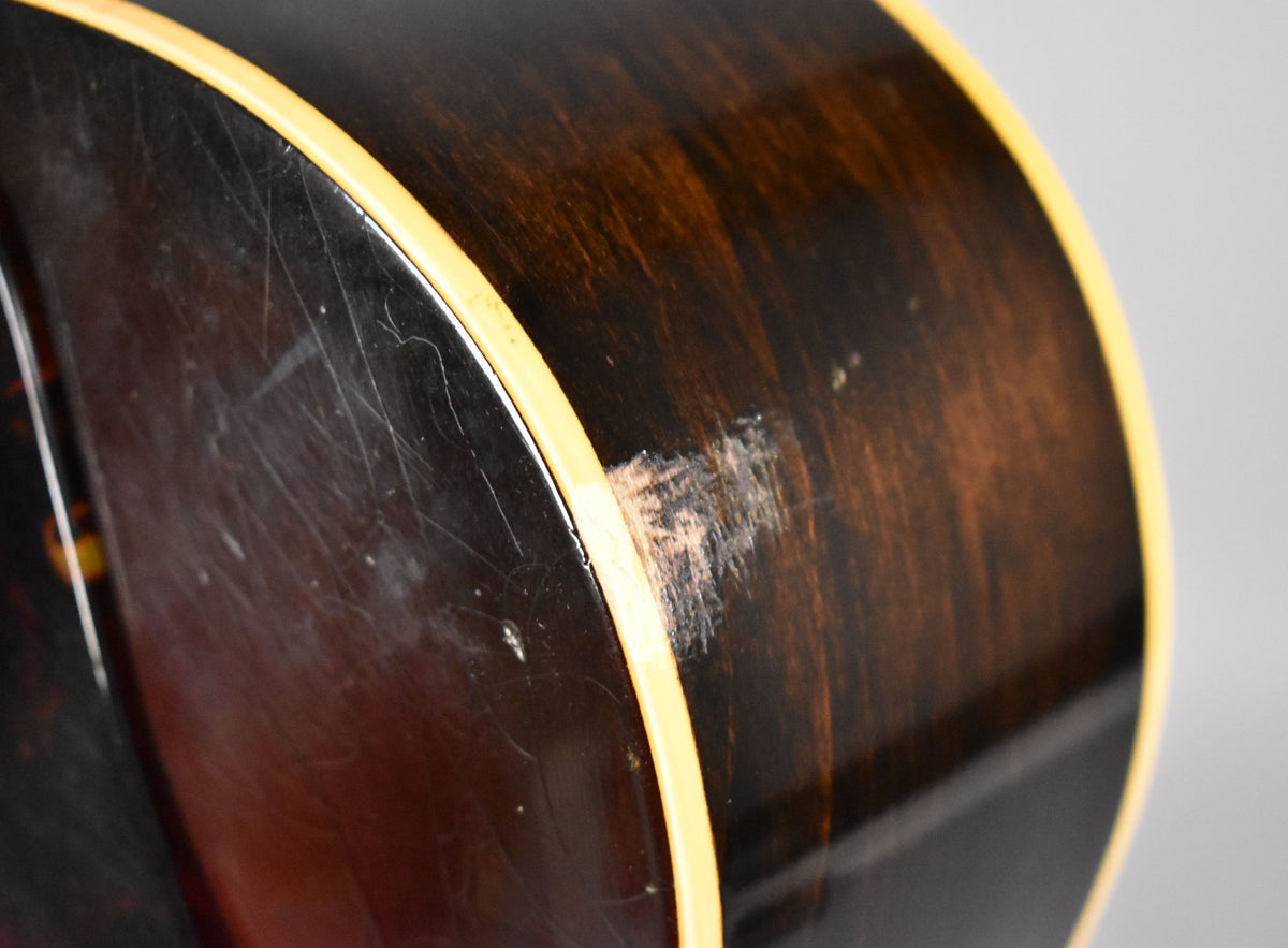 Close-up of the guitar's lower bout, showing heavy finish wear, scratches, and checking on the dark sunburst body and binding.