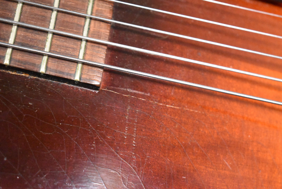 Close-up of the sunburst body and lower fretboard, showing heavy finish checking, scratches, and wear from strumming below the strings.