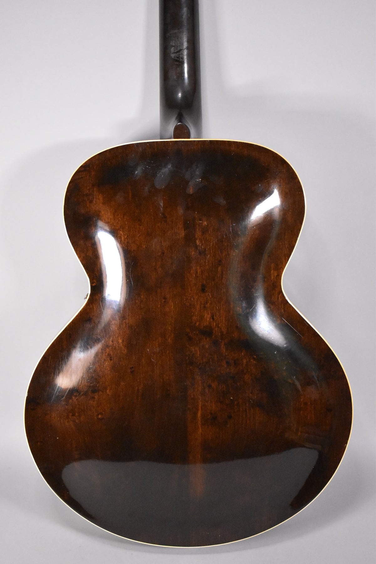 The guitar's dark sunburst back and neck are shown from behind, with visible finish wear, scratches, and binding around the body.