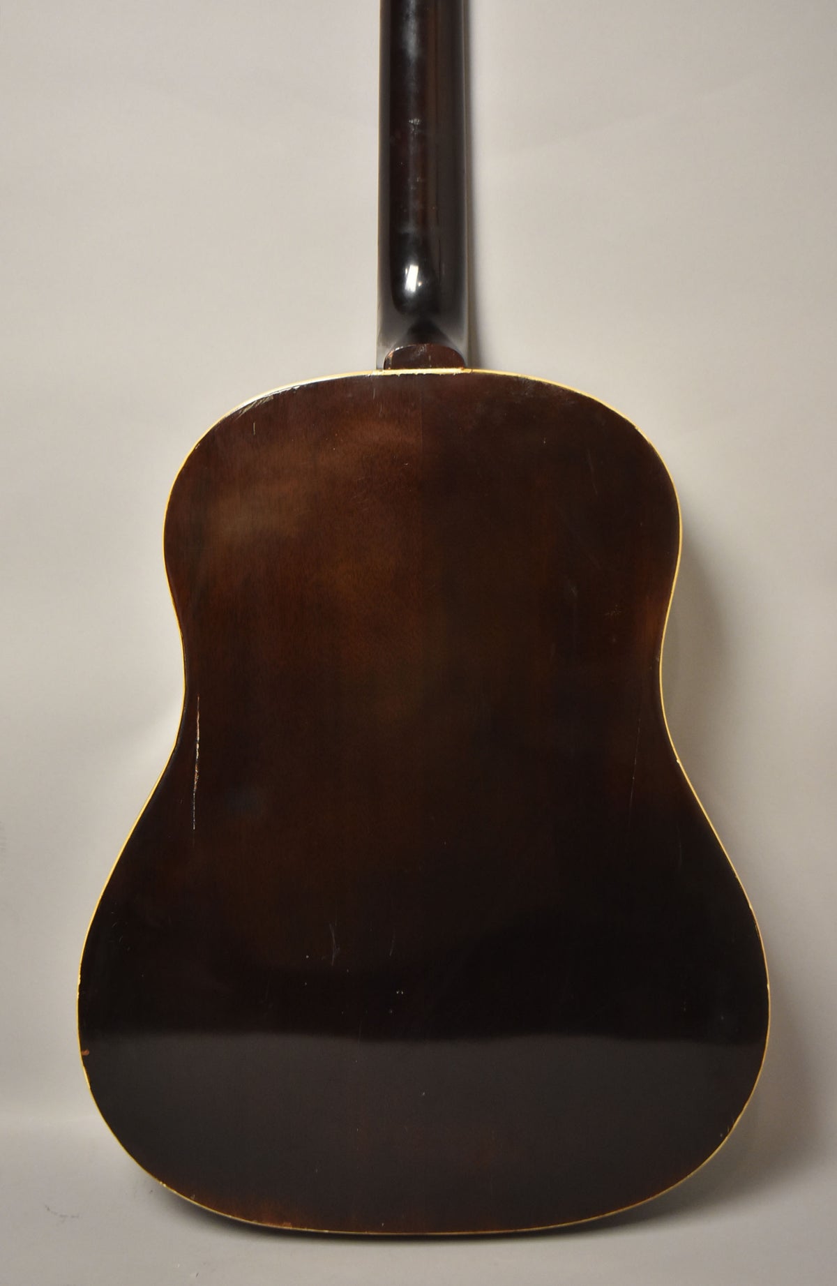 The guitar's dark sunburst back and neck are visible, with binding around the body and some light scratches and wear.