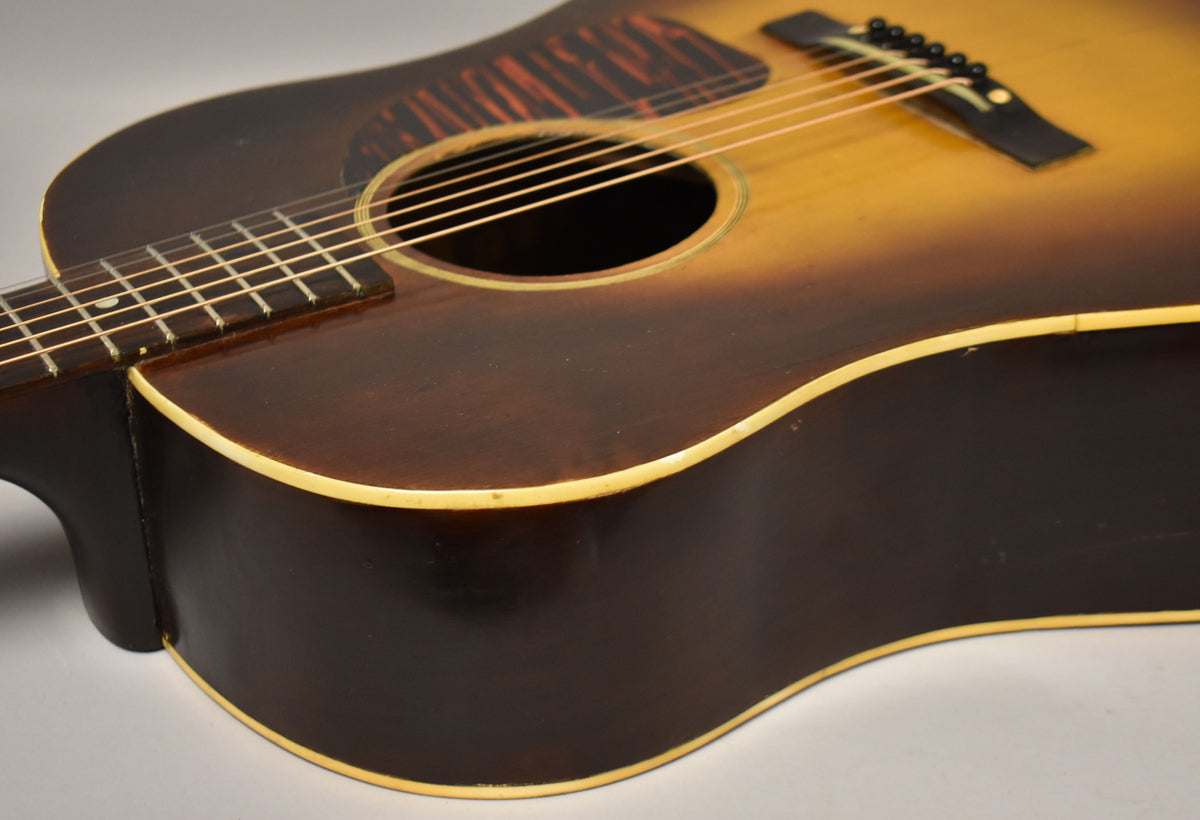 Close-up of the guitar's lower bout and waist, showing the dark sunburst finish, cream binding, and some minor wear.