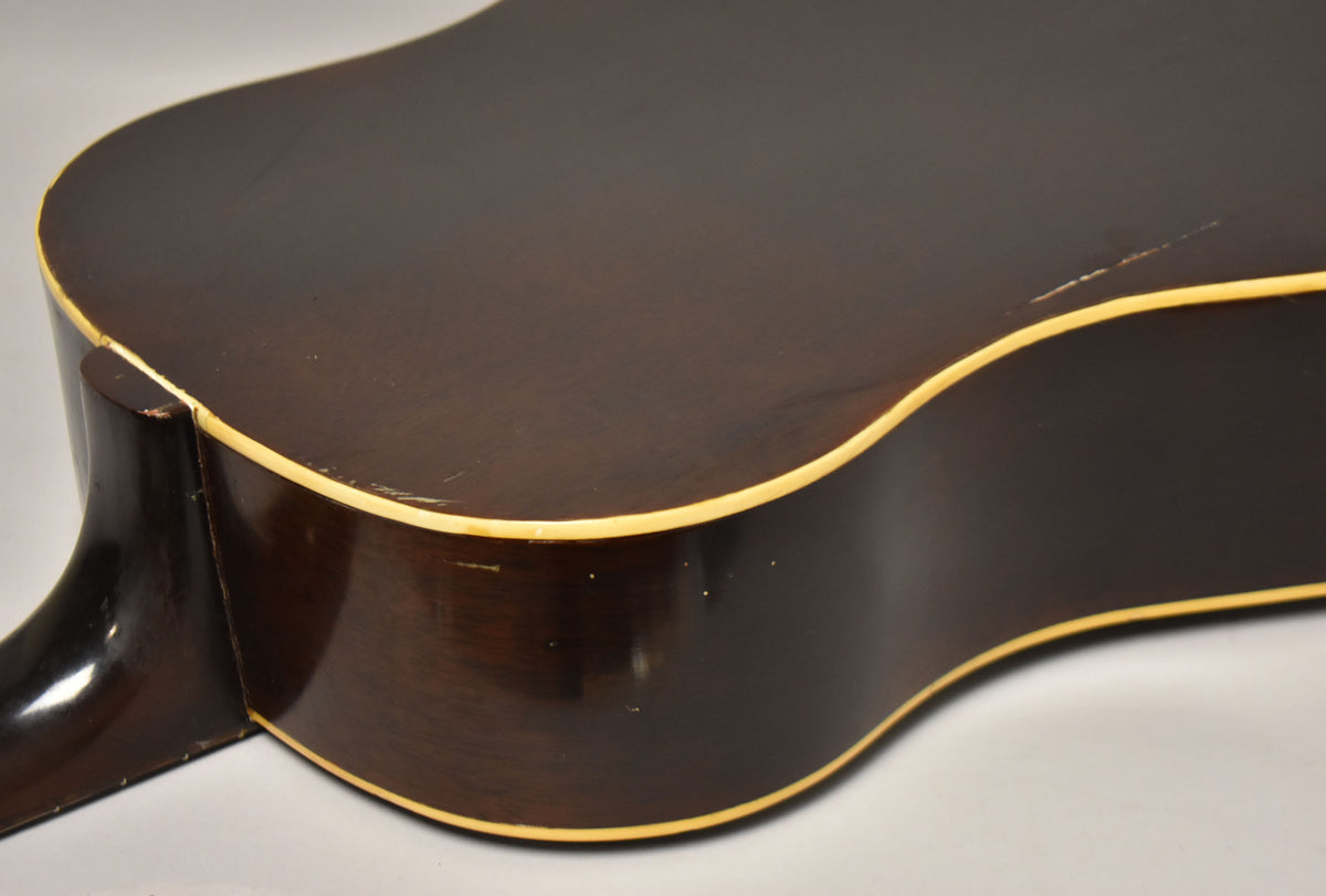 The lower bout of the dark sunburst acoustic guitar, showing the neck heel, body binding, and finish wear on the top and side.