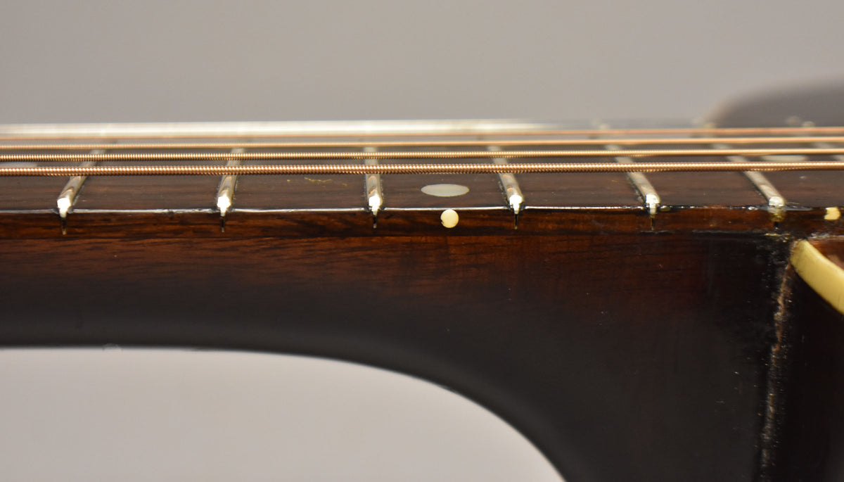 Close-up of the dark brown fretboard and neck, showing light wear on the frets and a small white dot inlay on the 7th fret.