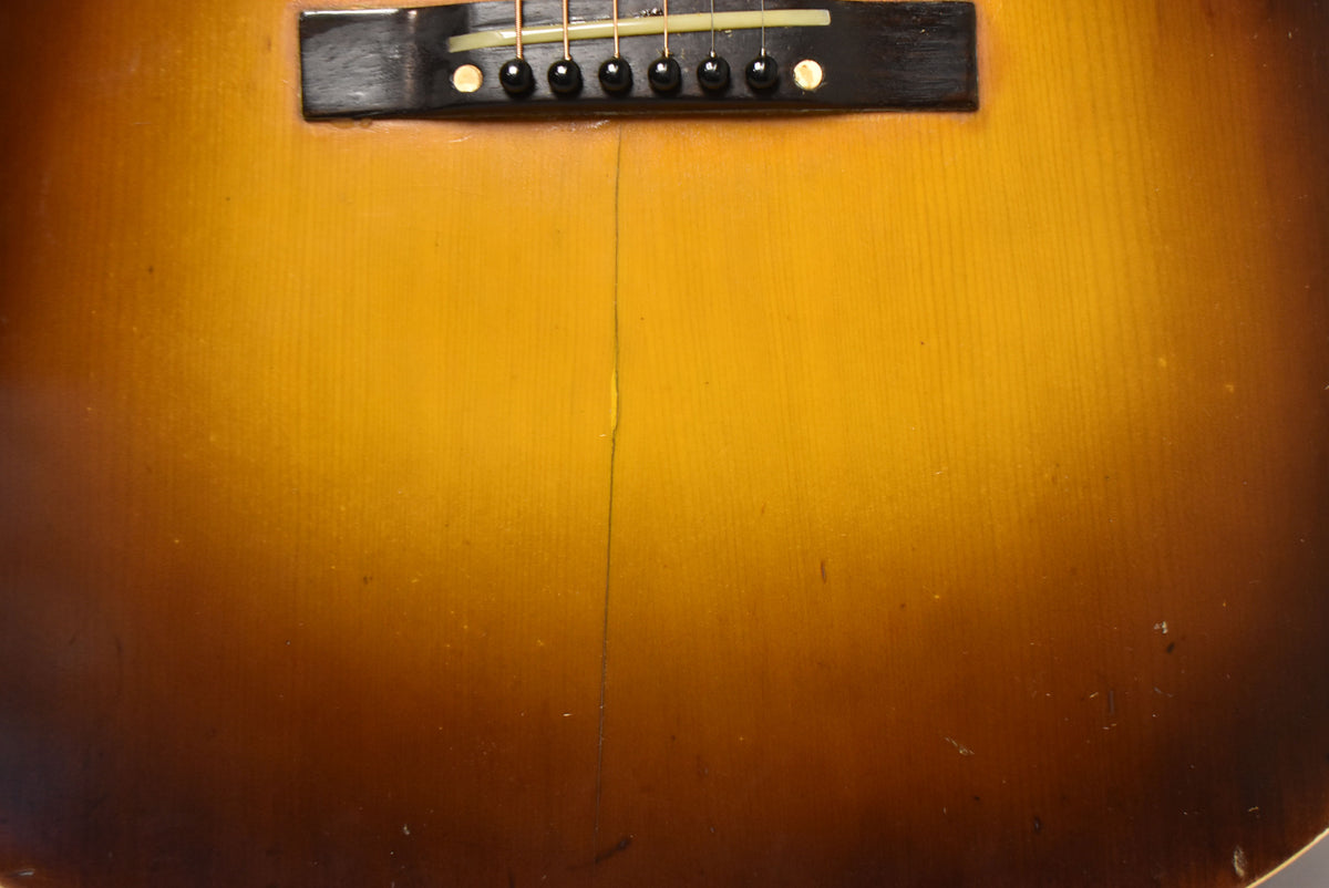Close-up of the sunburst body, showing the dark bridge with six black pins and a long, thin crack running down the center.
