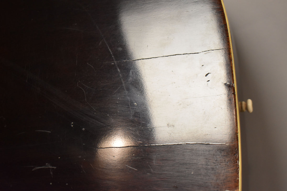 Close-up of the guitar's dark sunburst top, showing two long cracks, many scratches, and some small chips in the finish near the binding.