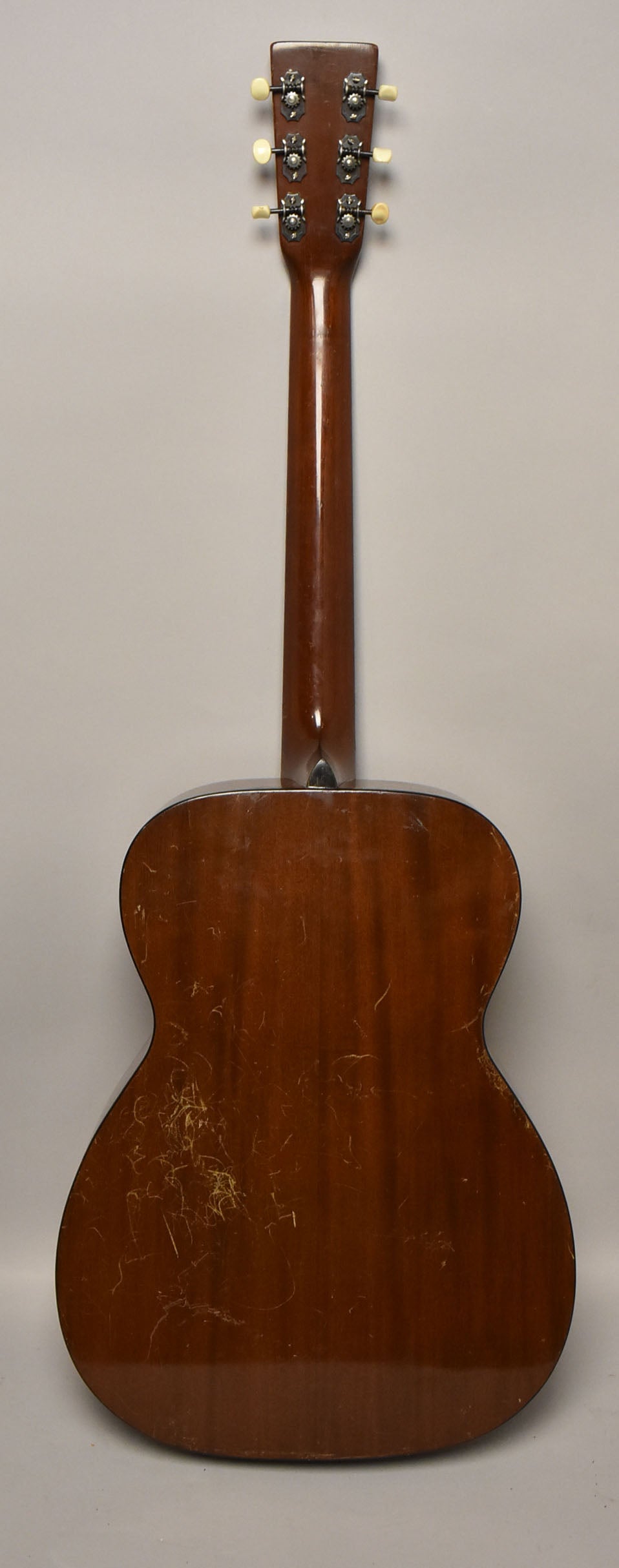 Full rear view of the dark brown acoustic guitar, showing the headstock with six cream tuners and heavy finish checking on the body.