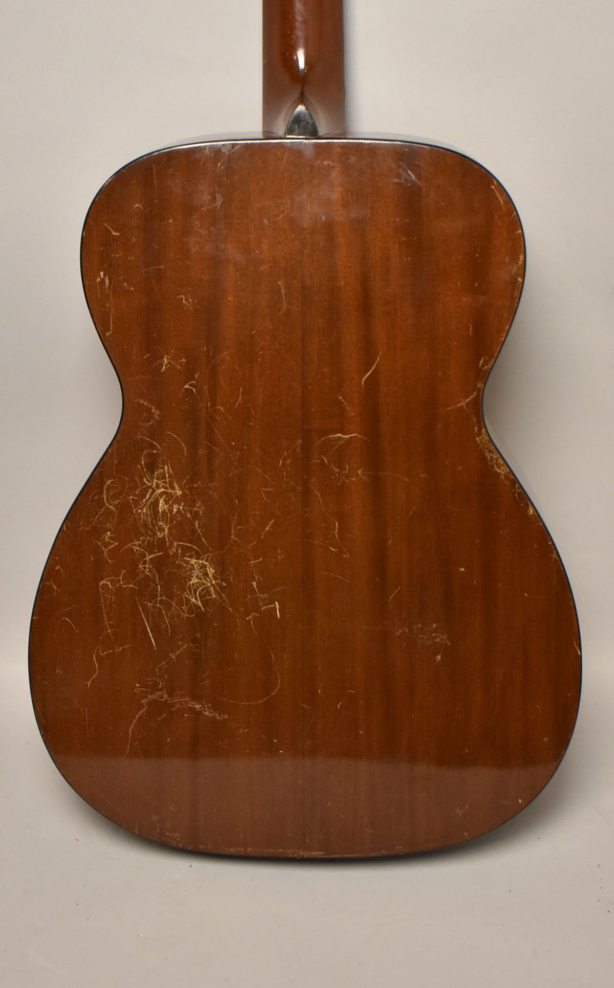The guitar's dark brown back is shown, with extensive finish checking and scratches, especially on the lower bout.