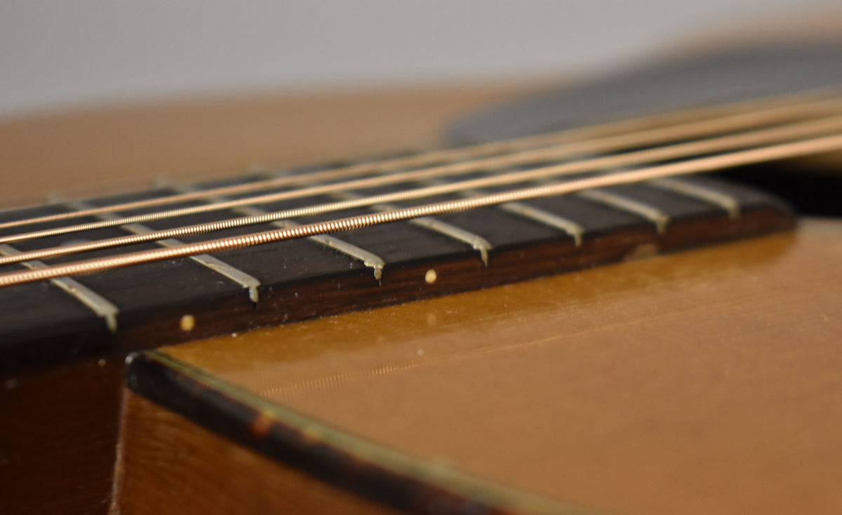 Close-up of the guitar's natural finish body and dark fretboard with light frets and dot inlays, showing light wear and checking.