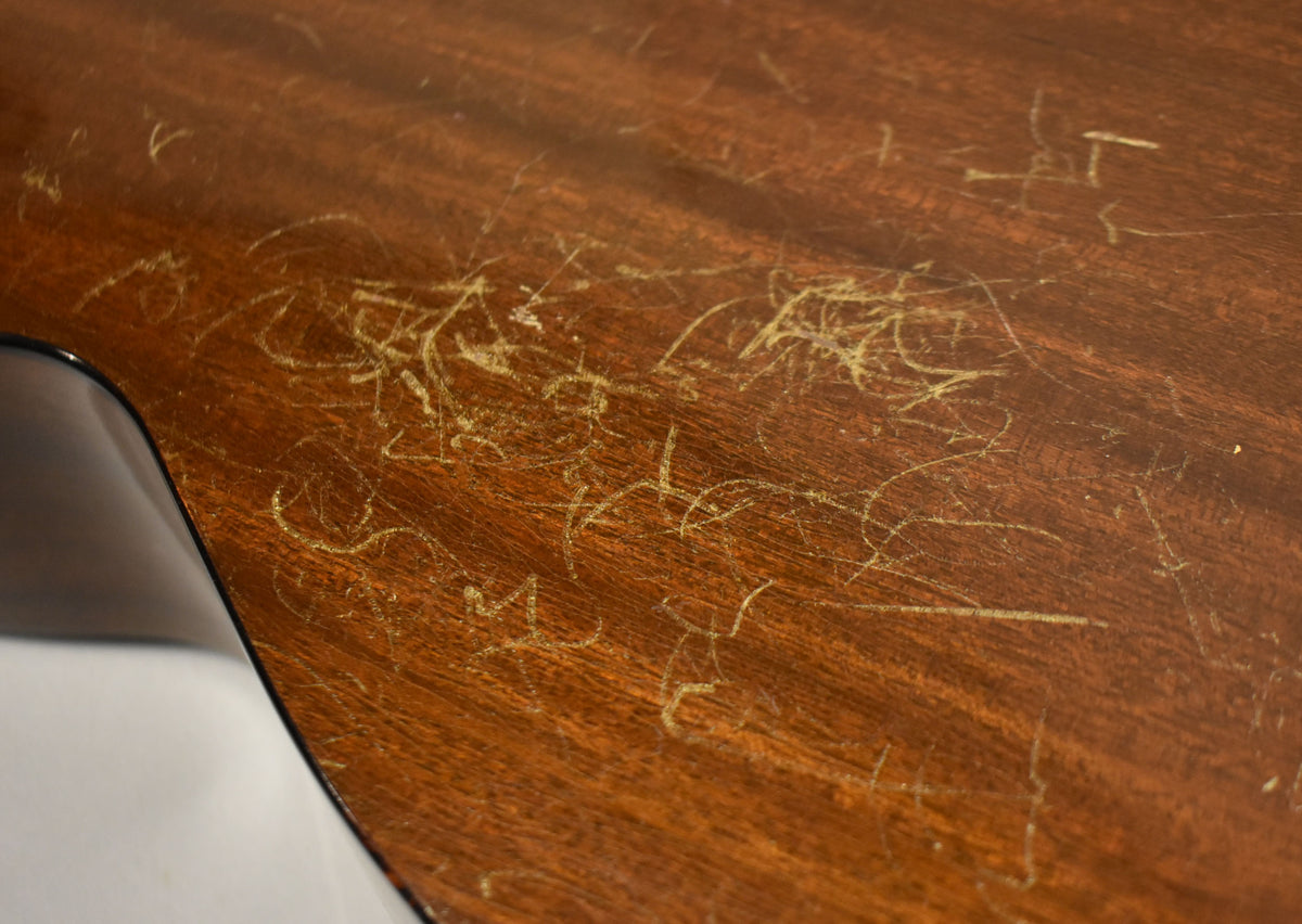 Close-up of the guitar's dark brown back, showing extensive light-colored scratches and wear across the entire surface.