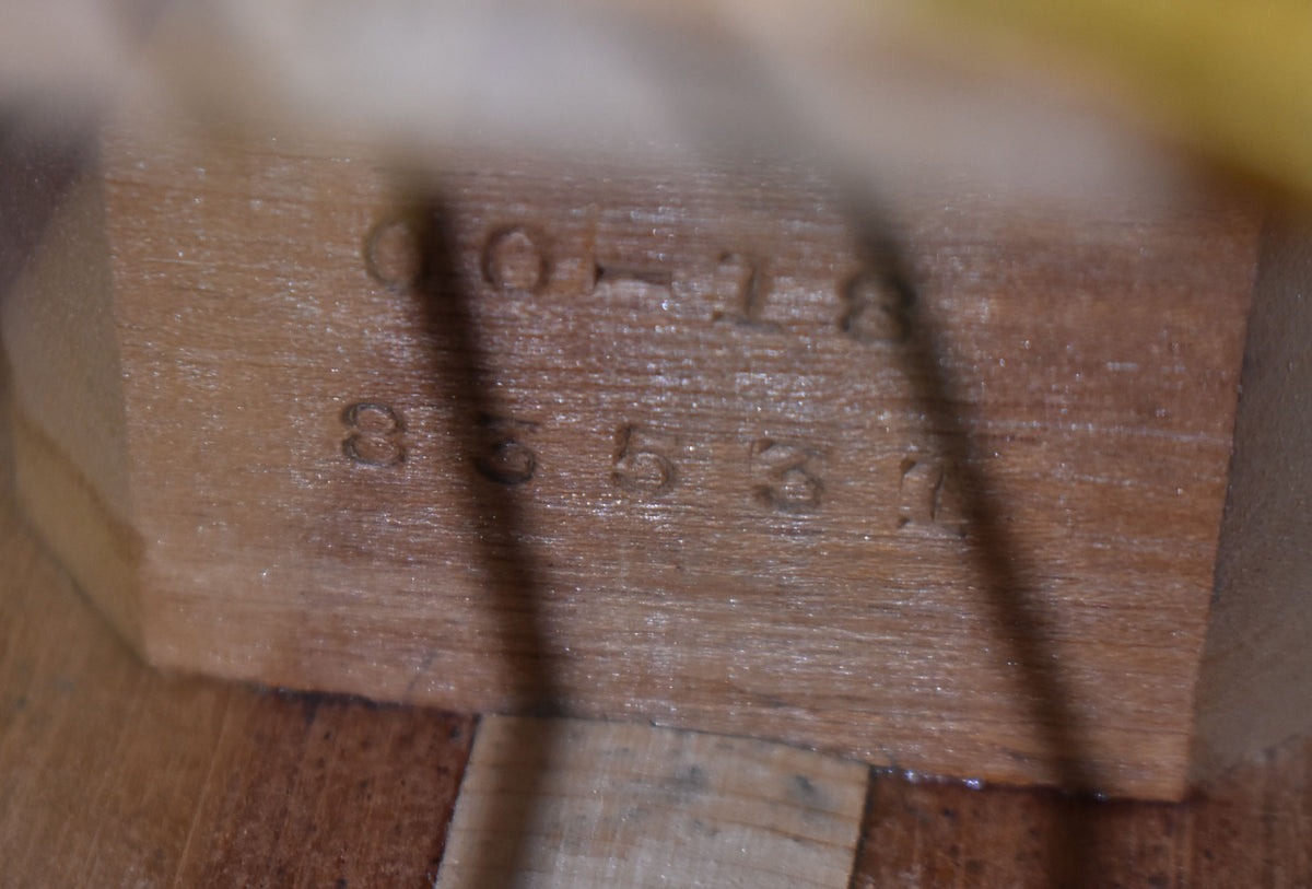 Close-up of the guitar's interior neck block, showing stamped numbers "00-18" and "85530" on the light brown wood.