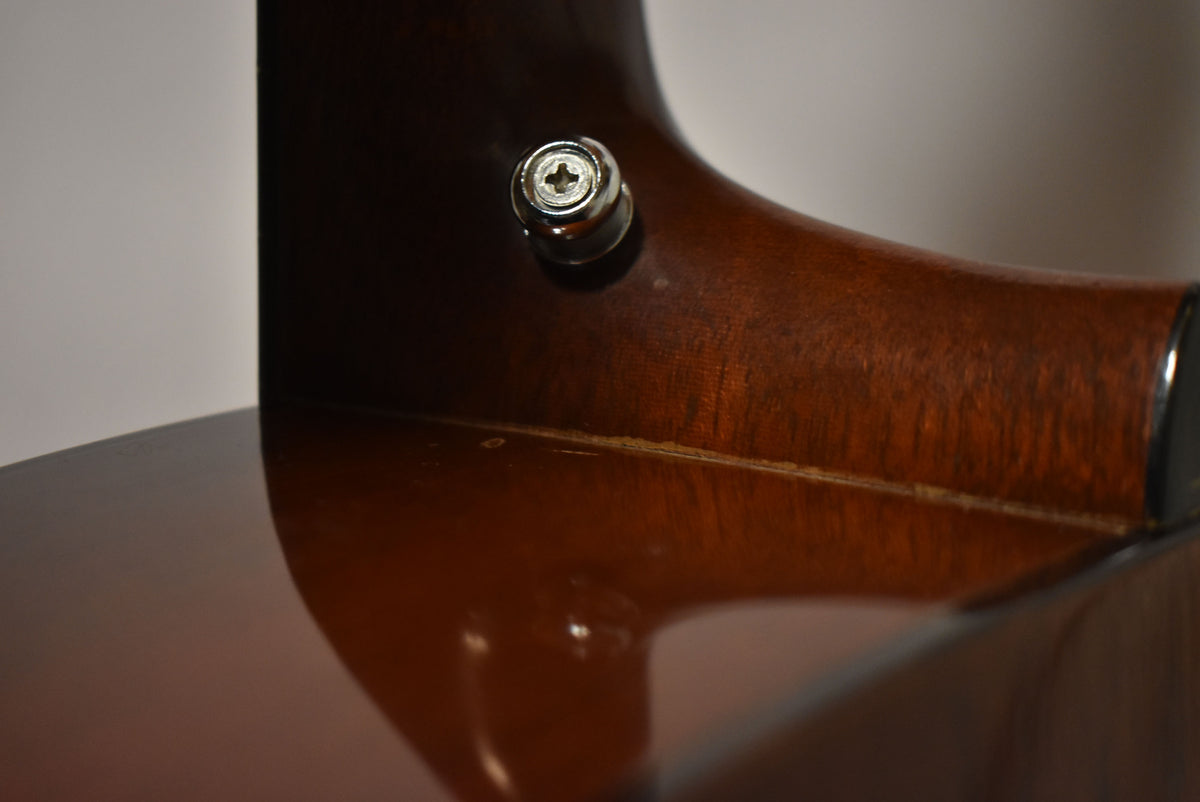 Close-up of the guitar's neck heel and upper bout, showing a chrome strap button and some finish wear along the neck joint.