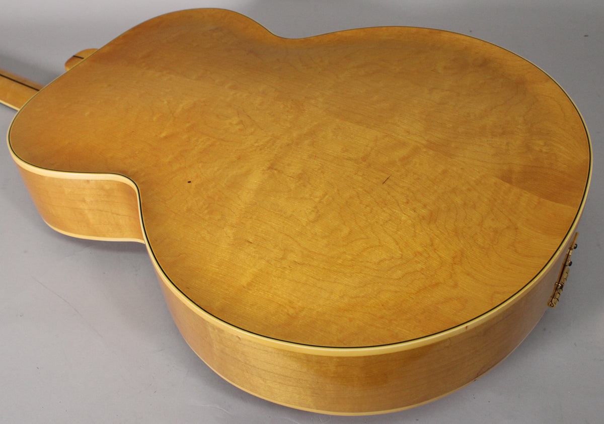 The guitar's natural finish back and sides show light flame figuring, with a few small dark spots and light scratches.