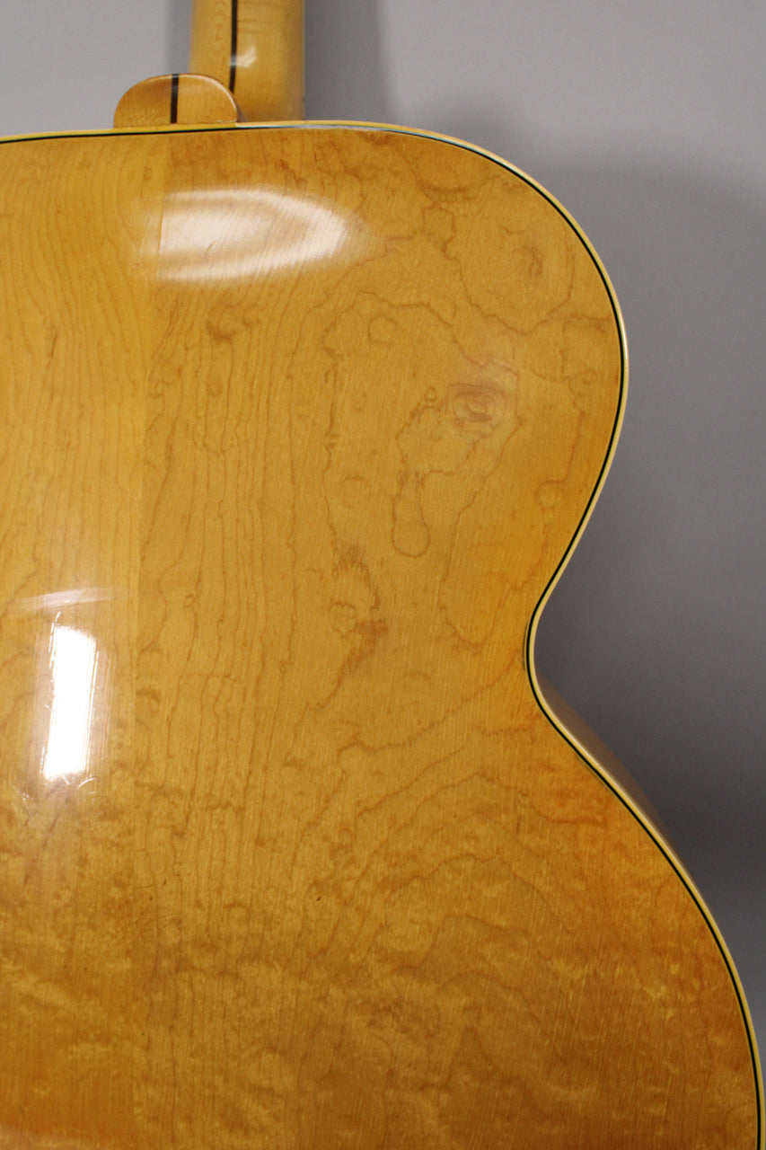 Close-up of the guitar's upper bout, showing the natural blonde finish with visible wood grain and light checking on the glossy surface.
