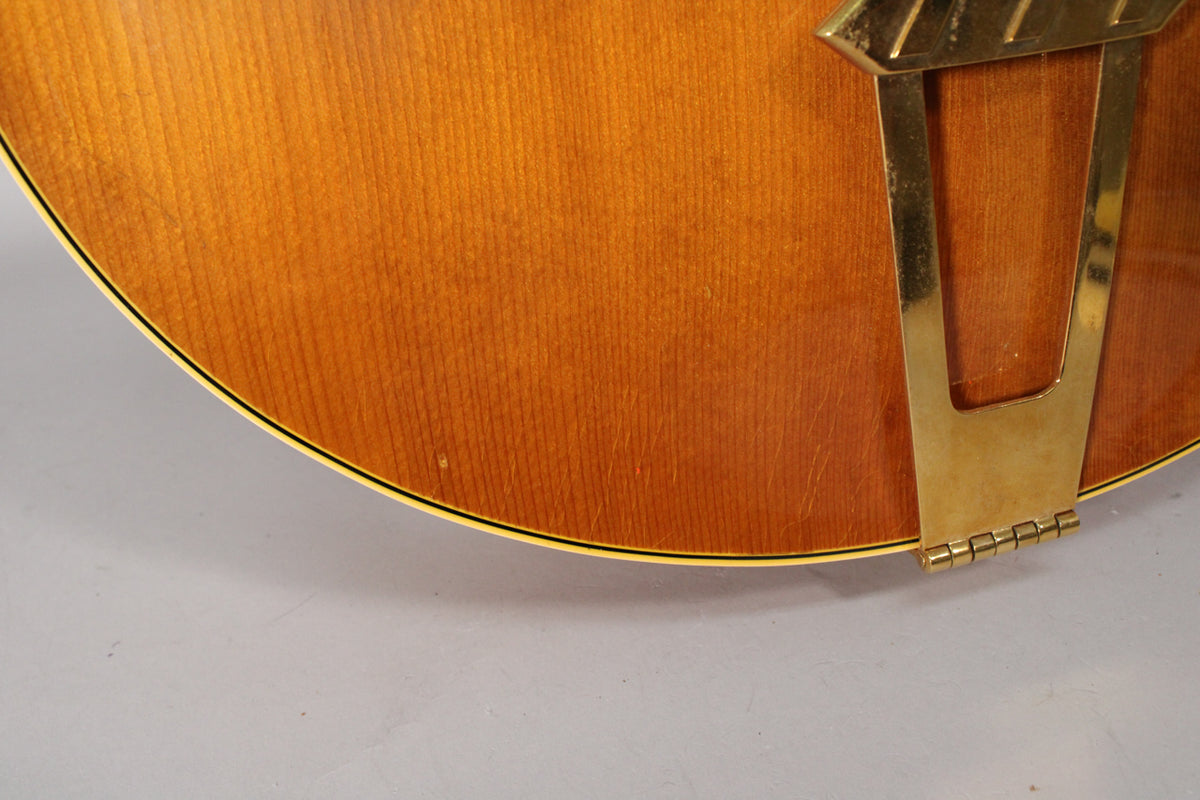 Close-up of the guitar's lower bout, showing the natural finish, binding, and the tarnished gold-plated trapeze tailpiece.