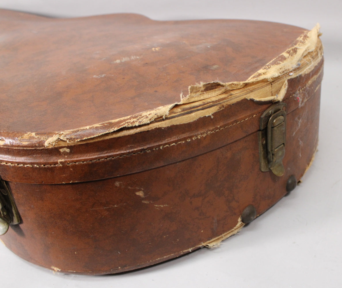 Close-up of the brown hard shell case, showing heavy wear and tear with torn covering around the edges and tarnished metal latches.