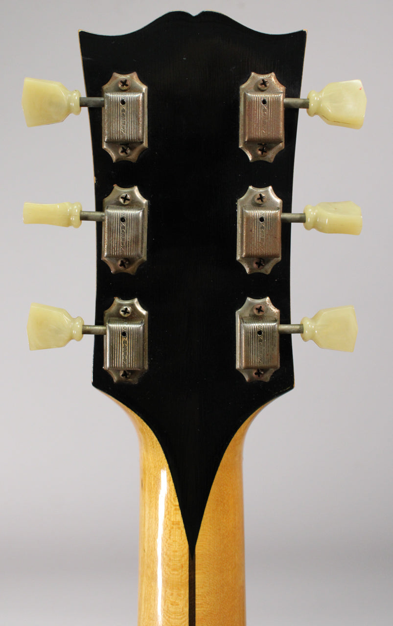 Rear view of the guitar's black headstock, showing six metal tuners with cream plastic buttons and a natural finish neck.