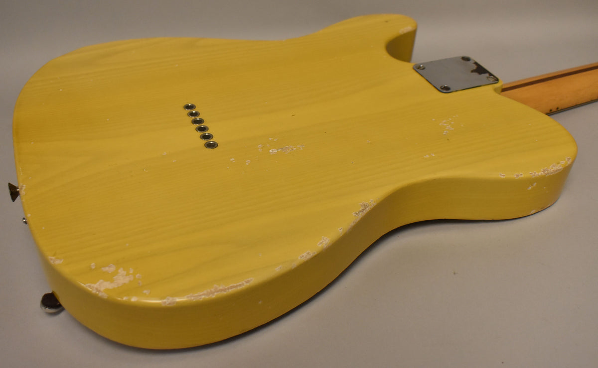The back of a butterscotch blonde guitar body, showing string-through ferrules, a neck plate, and heavy finish wear along the edges.