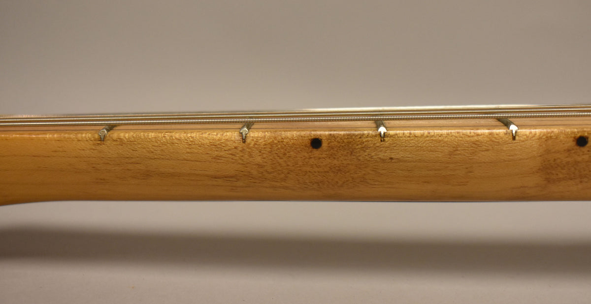 Close-up of the guitar's maple neck, showing string trees, a black dot inlay, and light wear on the wood.