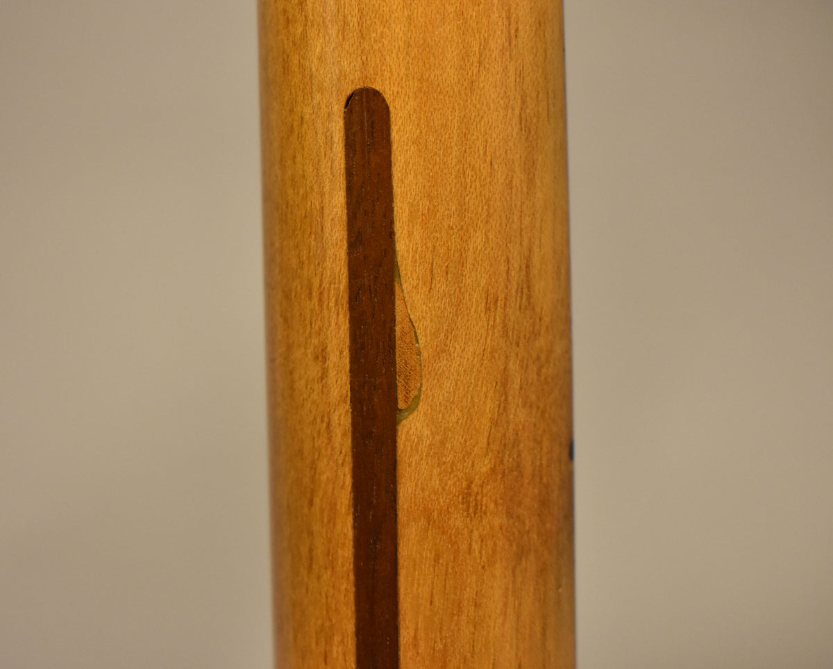 Close-up of the guitar's light blonde maple neck, showing a dark wood skunk stripe and a small chip in the finish near the stripe.