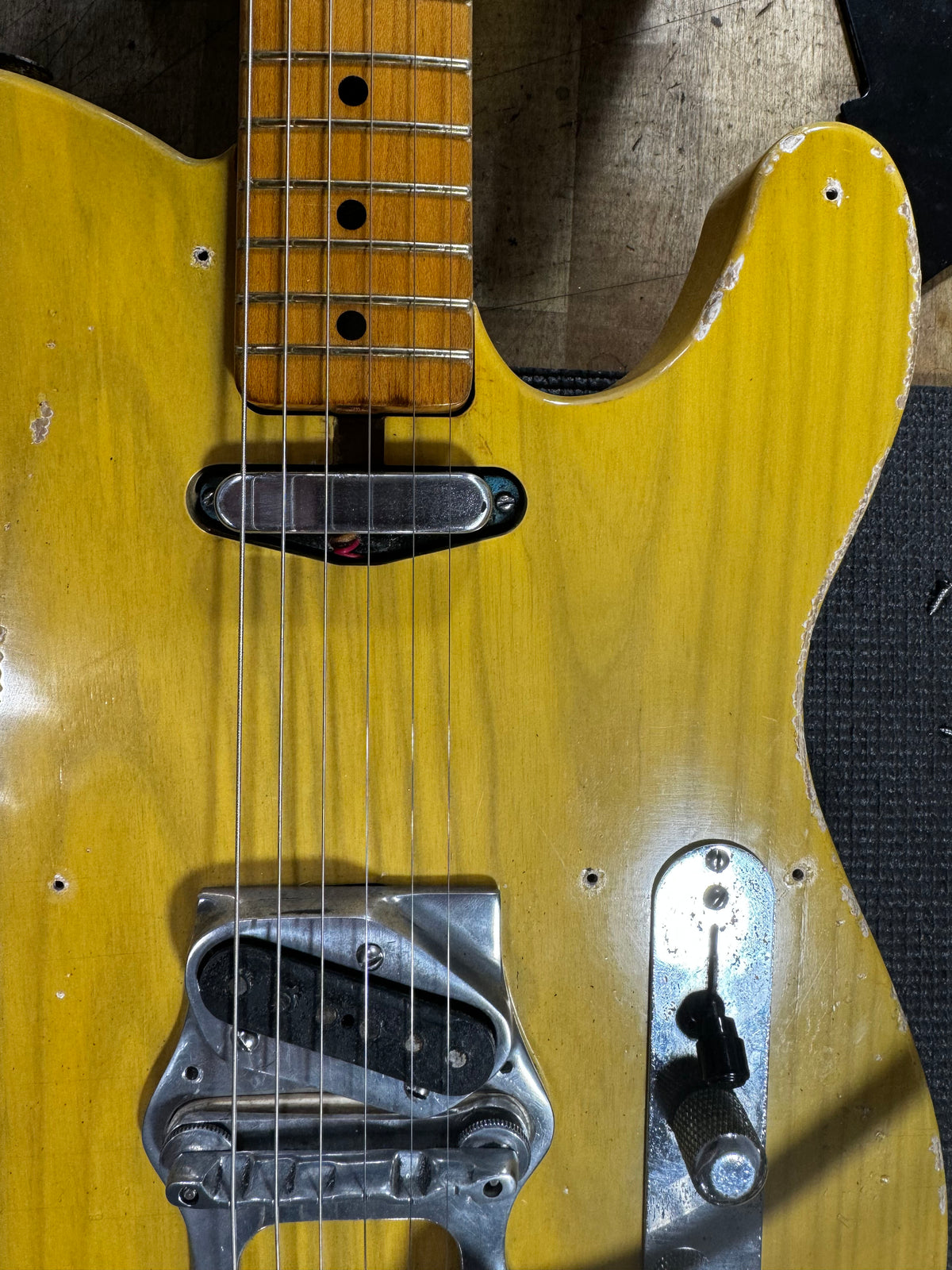 Close-up of a butterscotch blonde guitar body with a maple neck, showing a chrome neck pickup, bridge pickup, and control plate with heavy wear.