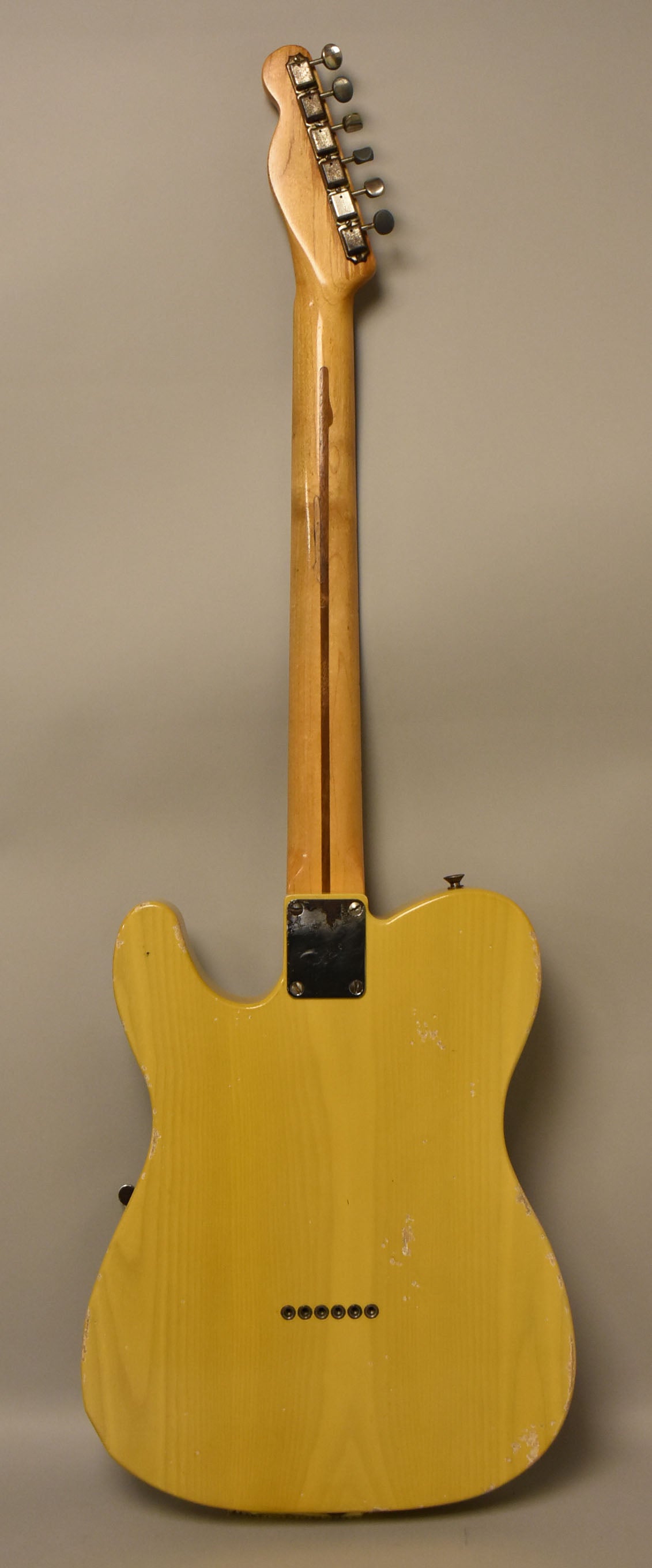 Full rear view of a butterscotch blonde guitar with a worn finish, showing string-through-body ferrules and a heavily played neck.