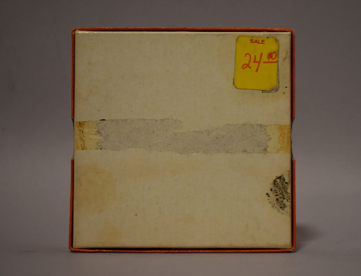 The top of a vintage orange box with a faded cream lid, showing a yellow "SALE 24.00" sticker and worn tape.