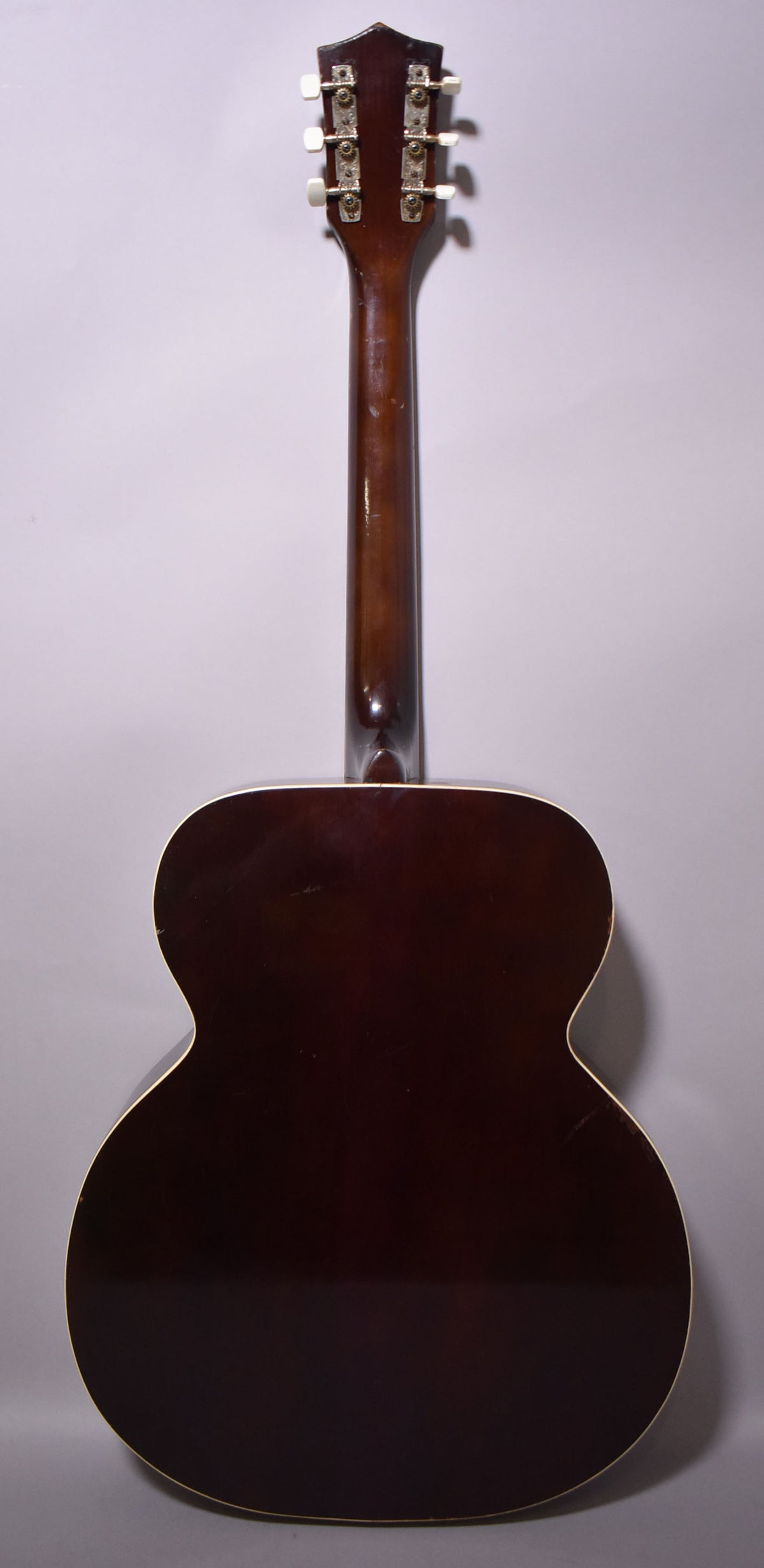 Full rear view of a dark brown acoustic guitar with a glossy finish, showing the headstock, neck, and body with some surface wear.