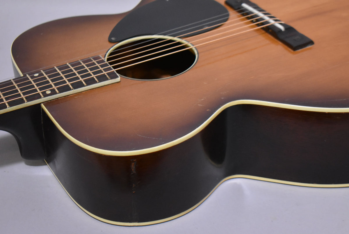 Close-up of the guitar's sunburst body, showing the soundhole, pickguard, bridge, and lower fretboard, with visible wear and checking.