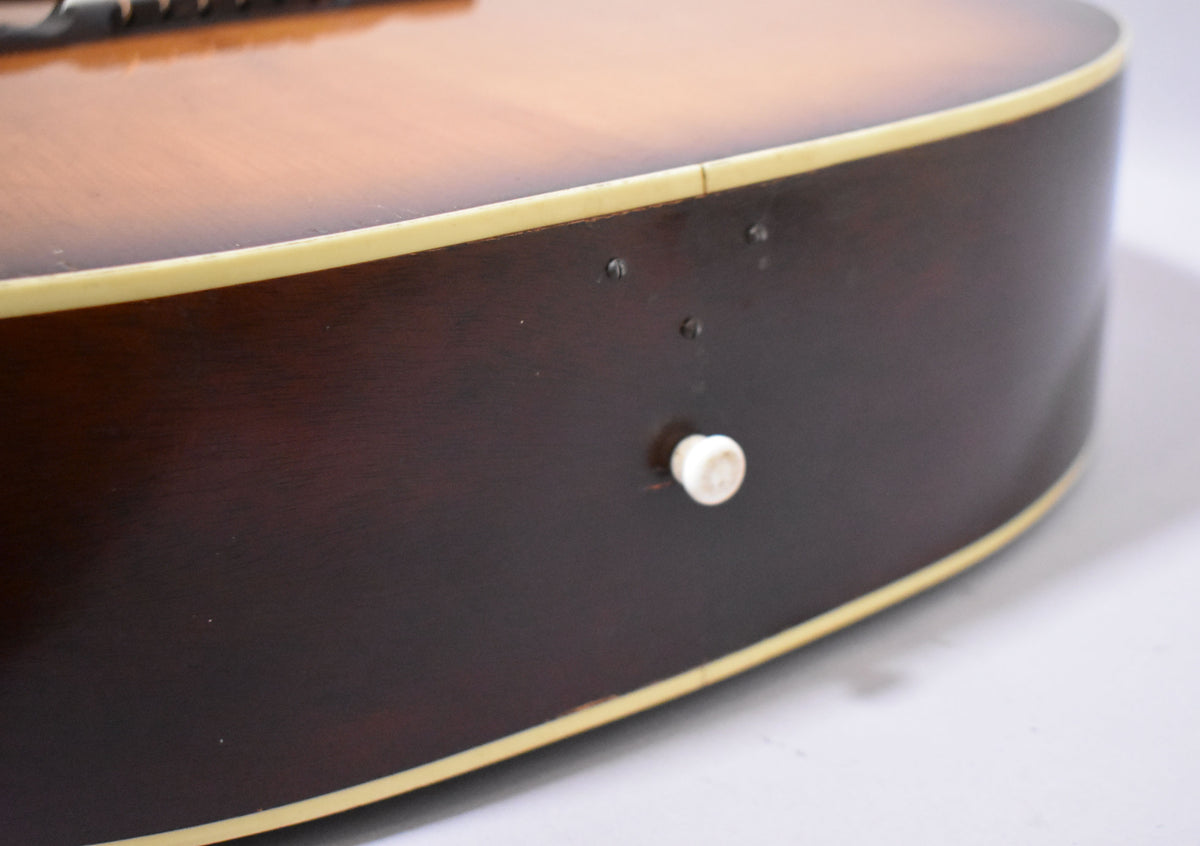 Close-up of the guitar's lower bout, showing the dark brown side with a cream binding, a white knob, and three small screw holes.