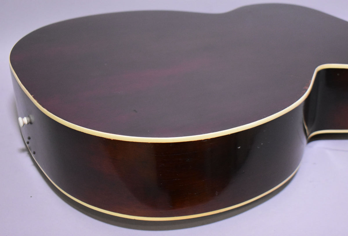 Close-up of the guitar's lower bout, showing the dark sunburst finish on the top and sides, with cream binding and some minor wear.