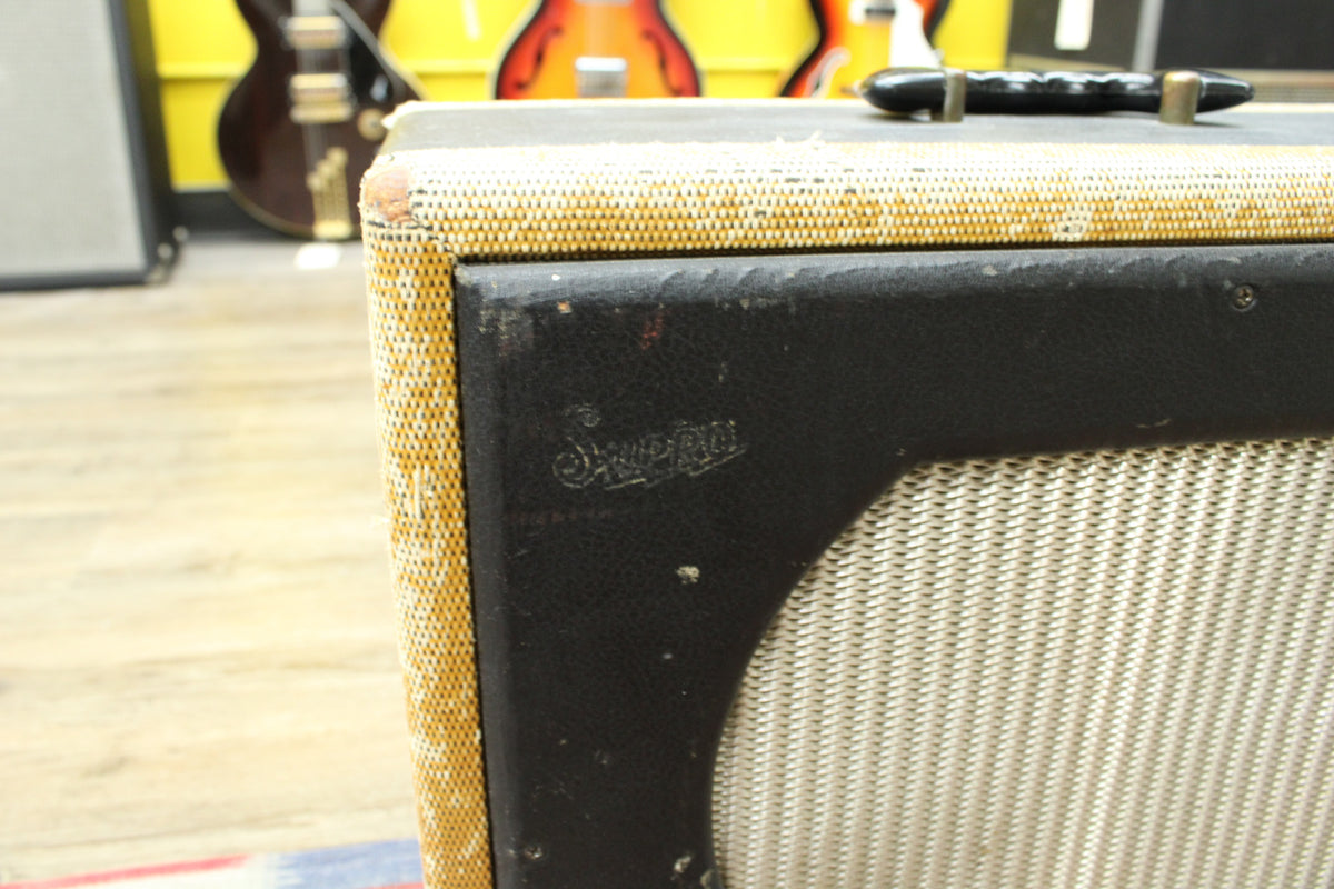 Close-up of the amp's upper right corner, showing worn tweed, black tolex, silver grille cloth, and a black handle on top.