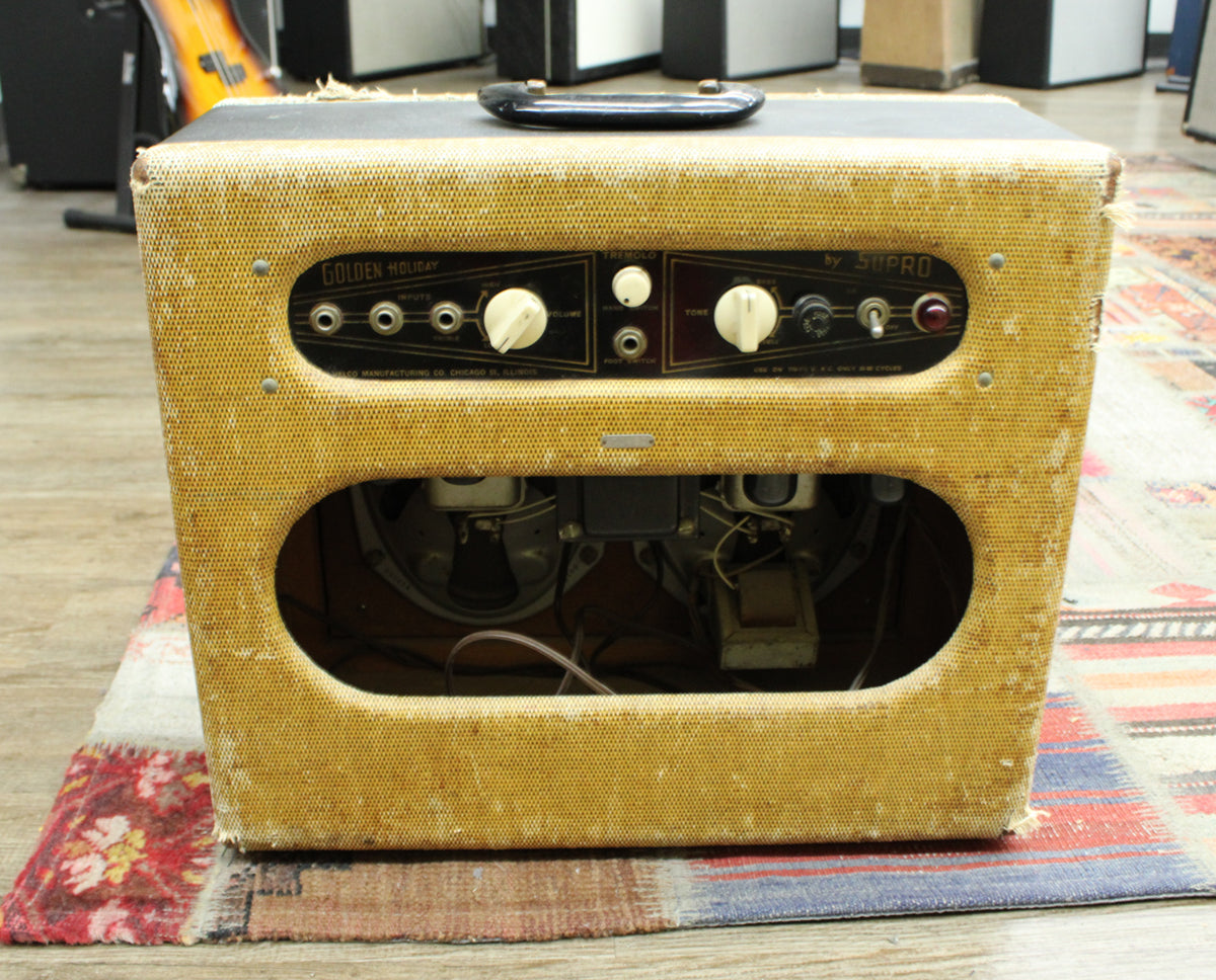 Front view of a tweed combo amp with a black control panel, white knobs, and two oval speaker cutouts revealing internal components.