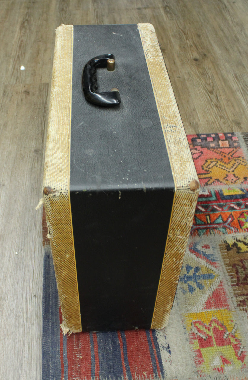 Top-down view of the amp's black top panel and tweed sides, showing the black plastic handle with brass hardware and worn tweed.