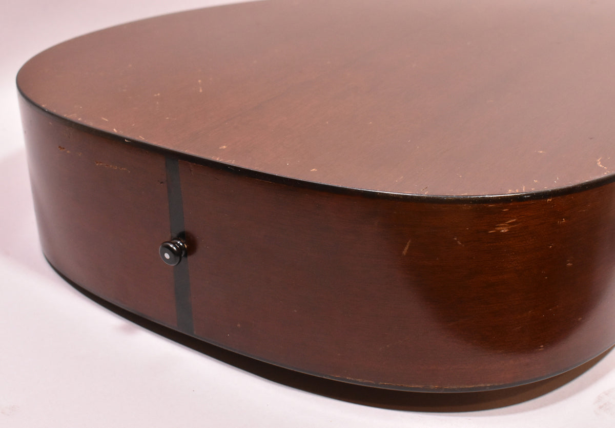 The guitar's lower bout, seen from the back, shows a dark brown natural finish with a black end pin and visible wear and scratches.
