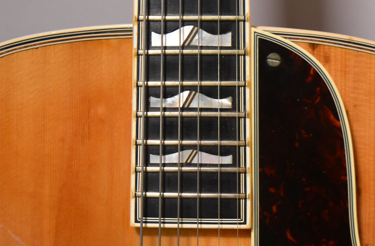 Close-up of the natural finish body and dark tortoiseshell pickguard, with the fretboard showing mother-of-pearl block inlays.