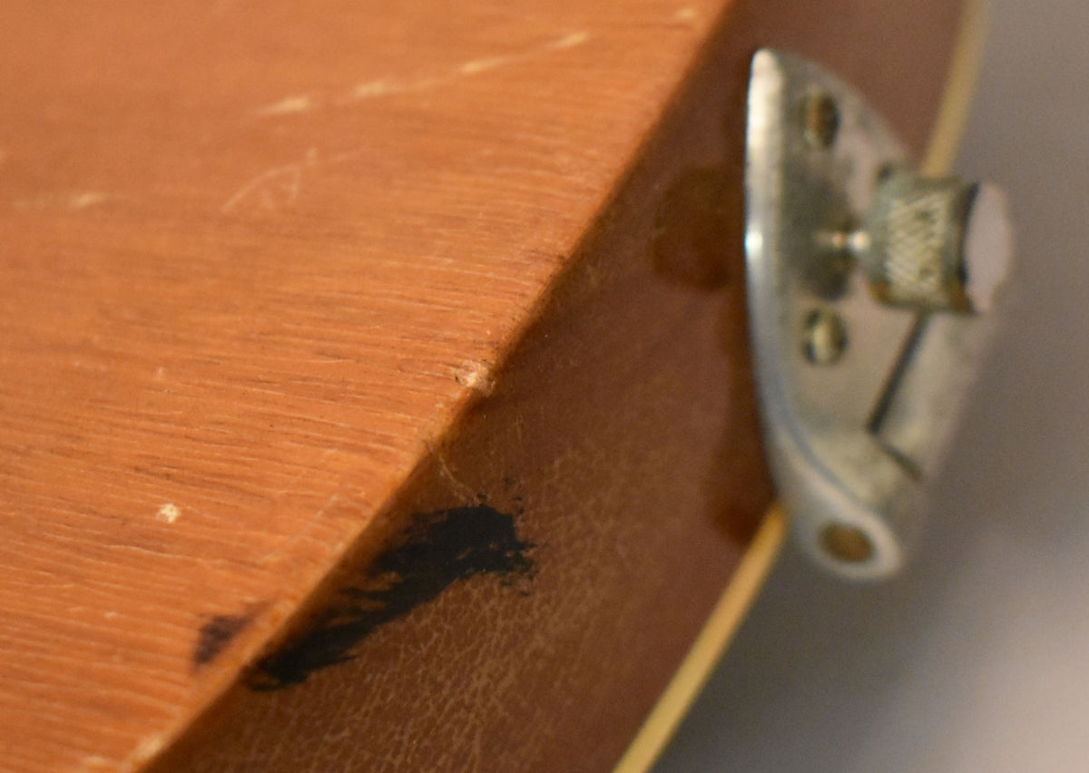 Close-up of the guitar's lower bout, showing a worn strap button, dark finish wear, and light checking on the reddish-brown body.