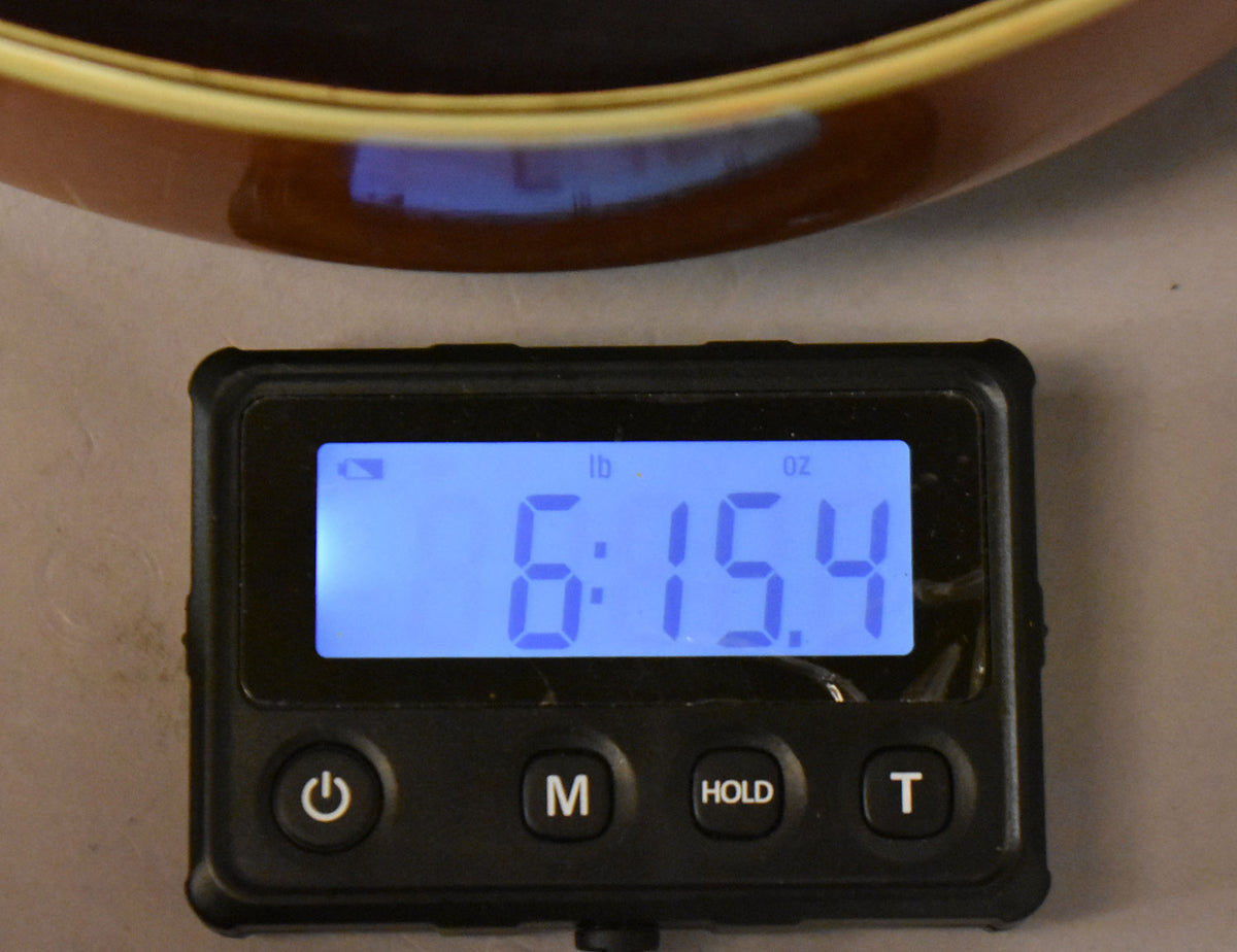 A digital scale shows the guitar's weight as 6 pounds, 15.4 ounces, with a brown guitar body visible at the top.