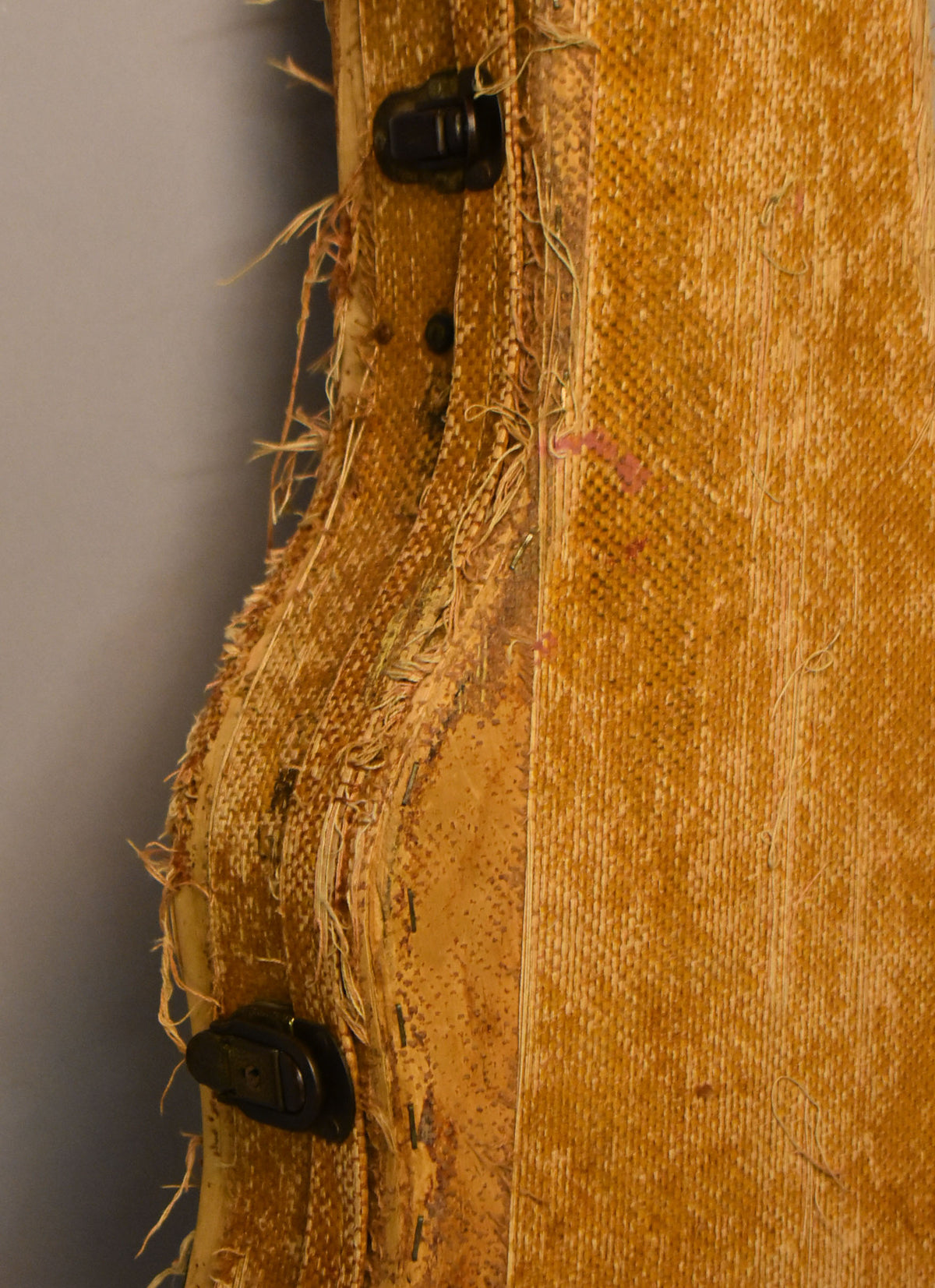 Close-up of the guitar's tan tweed hard case, showing worn, frayed edges, exposed wood, and two black latches on the left side.