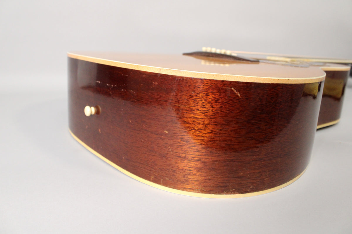 The guitar's lower bout, seen from the side, shows a dark reddish-brown finish with visible scratches and a cream endpin.