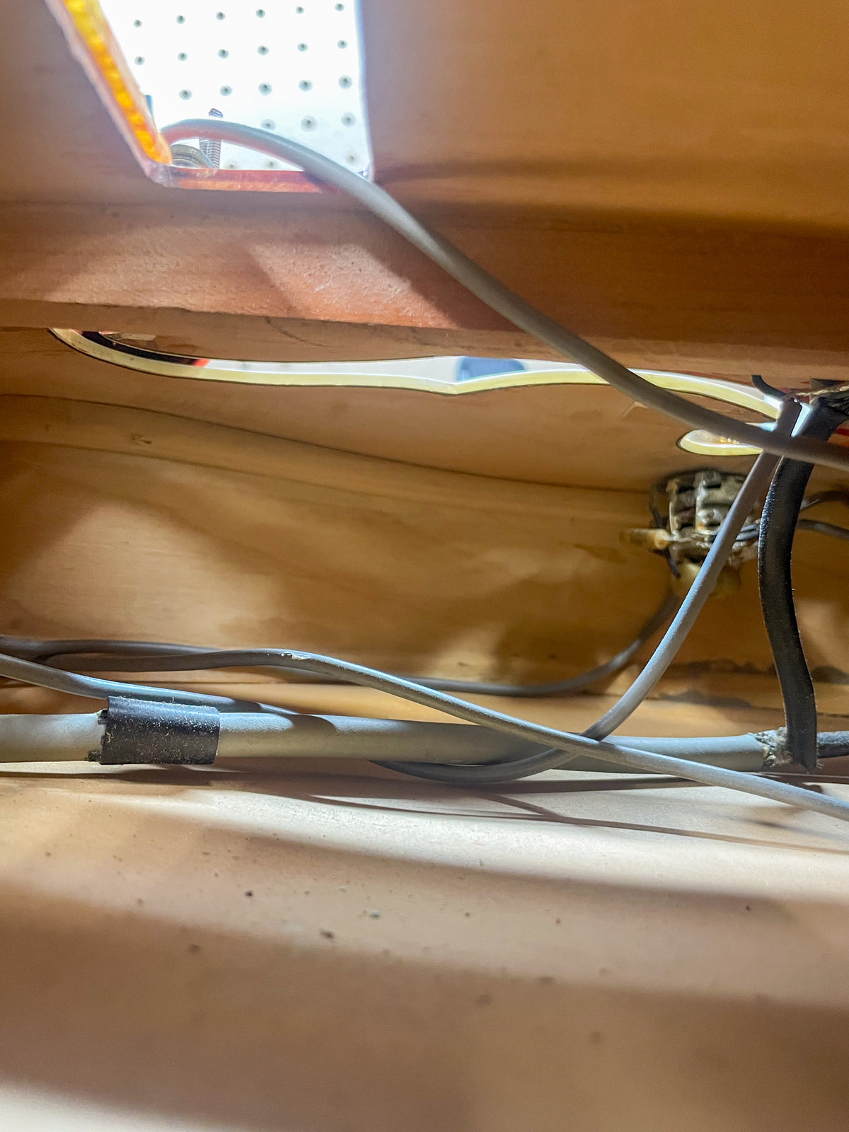 Interior view of the guitar body, showing wiring and the f-hole from the inside, with light wood and some dust.