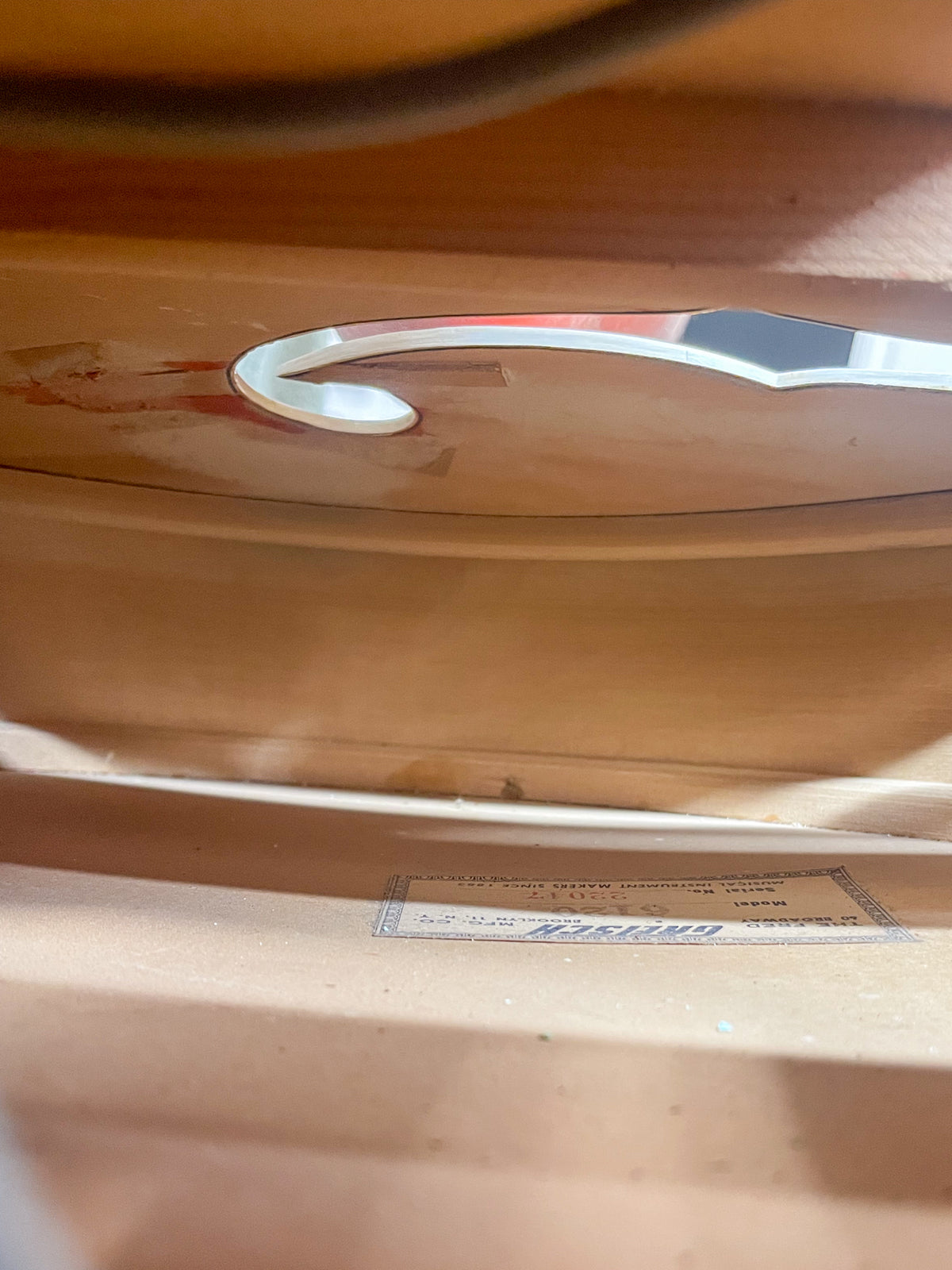 Looking down into the guitar's f-hole, revealing the light wood interior and a paper label with text.