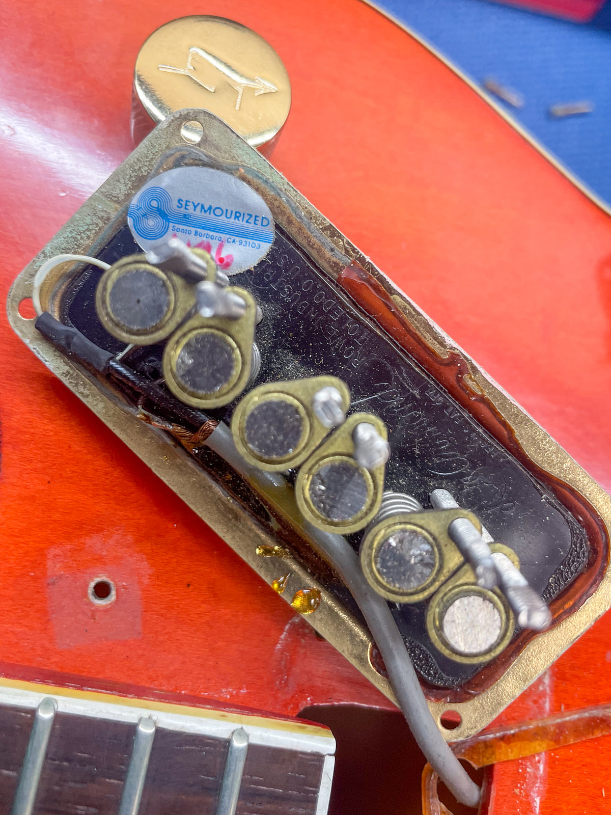 Close-up of the bridge pickup cavity, showing the gold pickup frame, exposed wiring, and a "Seymourized" sticker.