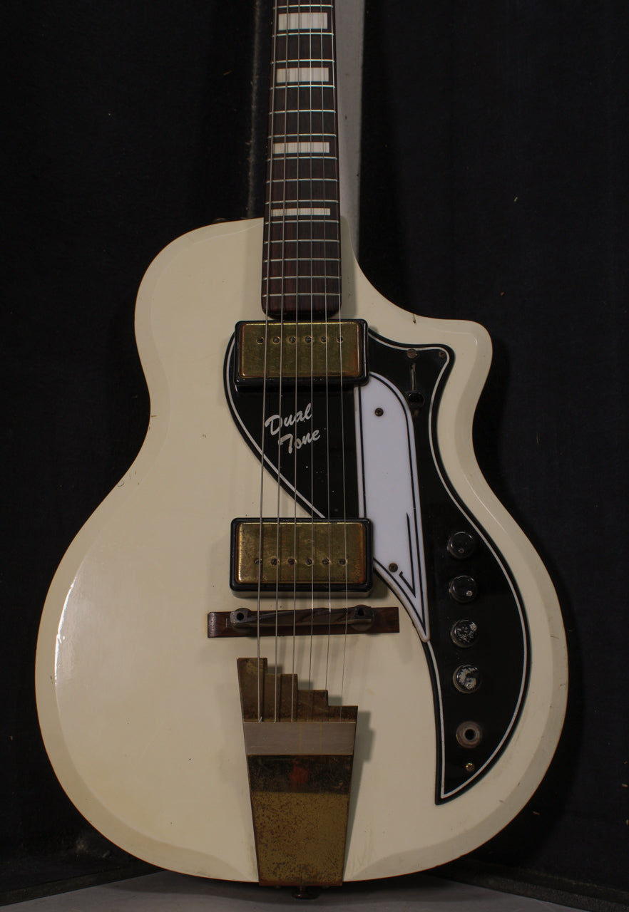 Full view of a vintage off-white electric guitar with two gold pickups, a black and white pickguard, and four black control knobs.