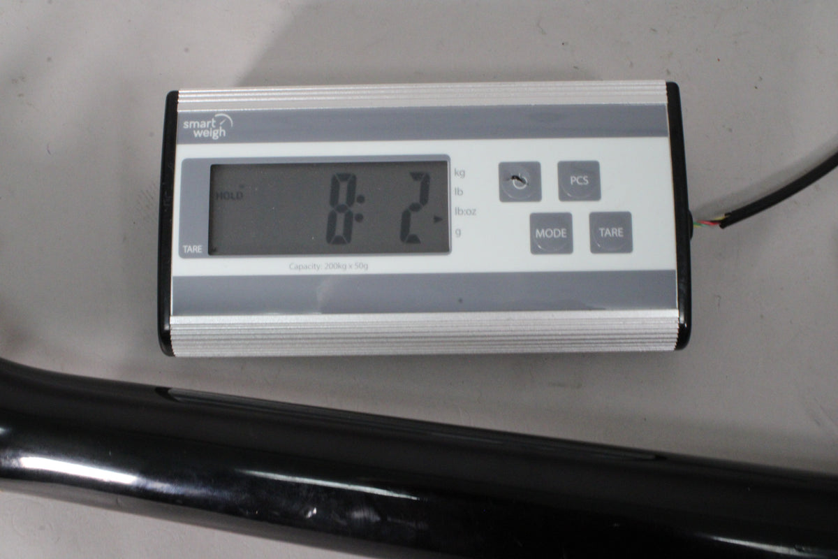 A digital scale displays "8.2-" in pounds, with a black guitar neck visible below, showing some minor surface wear.