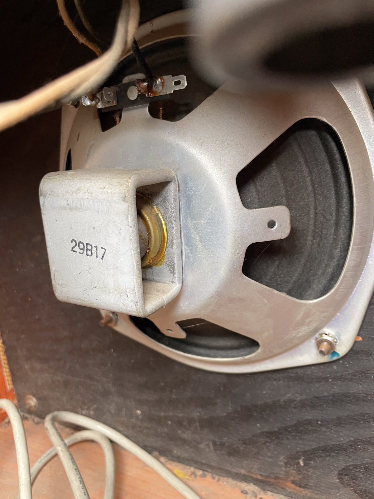 Close-up of the speaker's silver frame and black cone, showing soldered wires, a gold-colored magnet, and "29B17" stamped on the magnet cover.