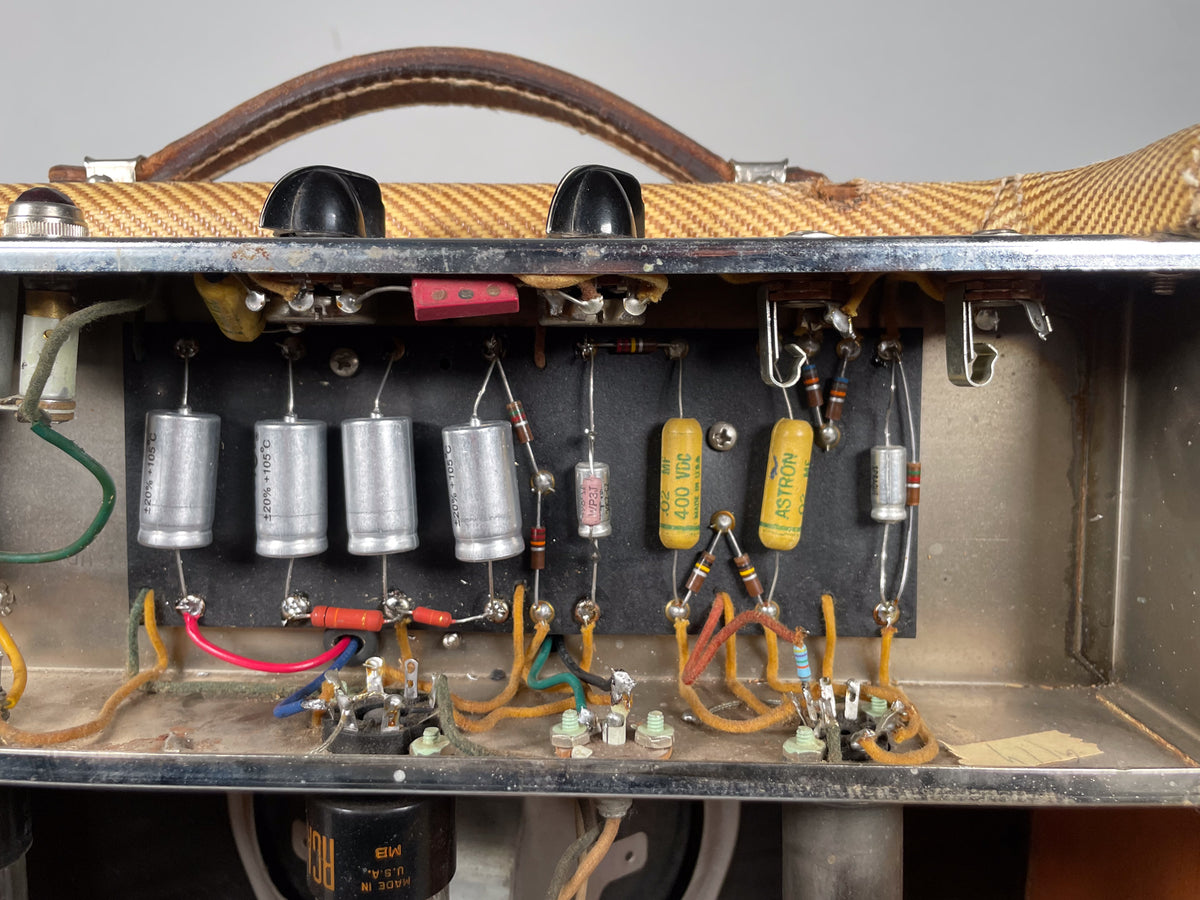 Top-down view of the amp's internal electronics, showing four large silver capacitors, yellow capacitors, and various resistors.