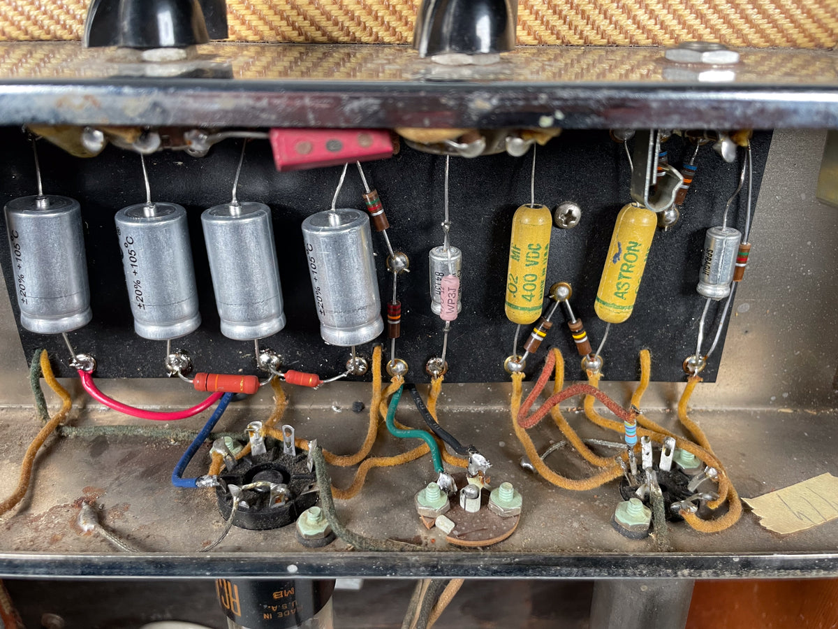 Close-up of the amp's internal wiring, showing four large silver capacitors, yellow and red components, and various wires.
